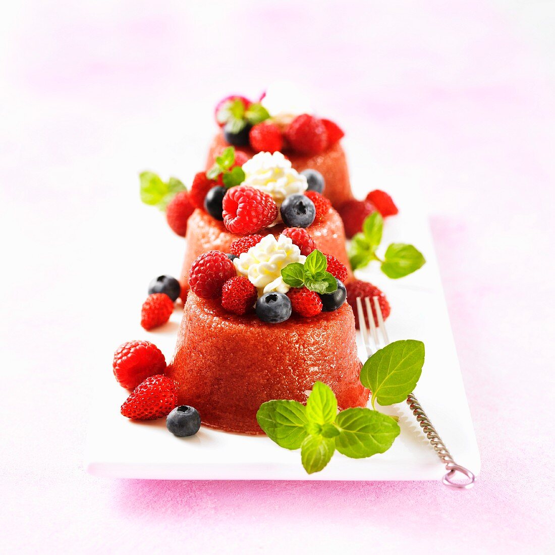 Three forest fruits puddings with cream and mint