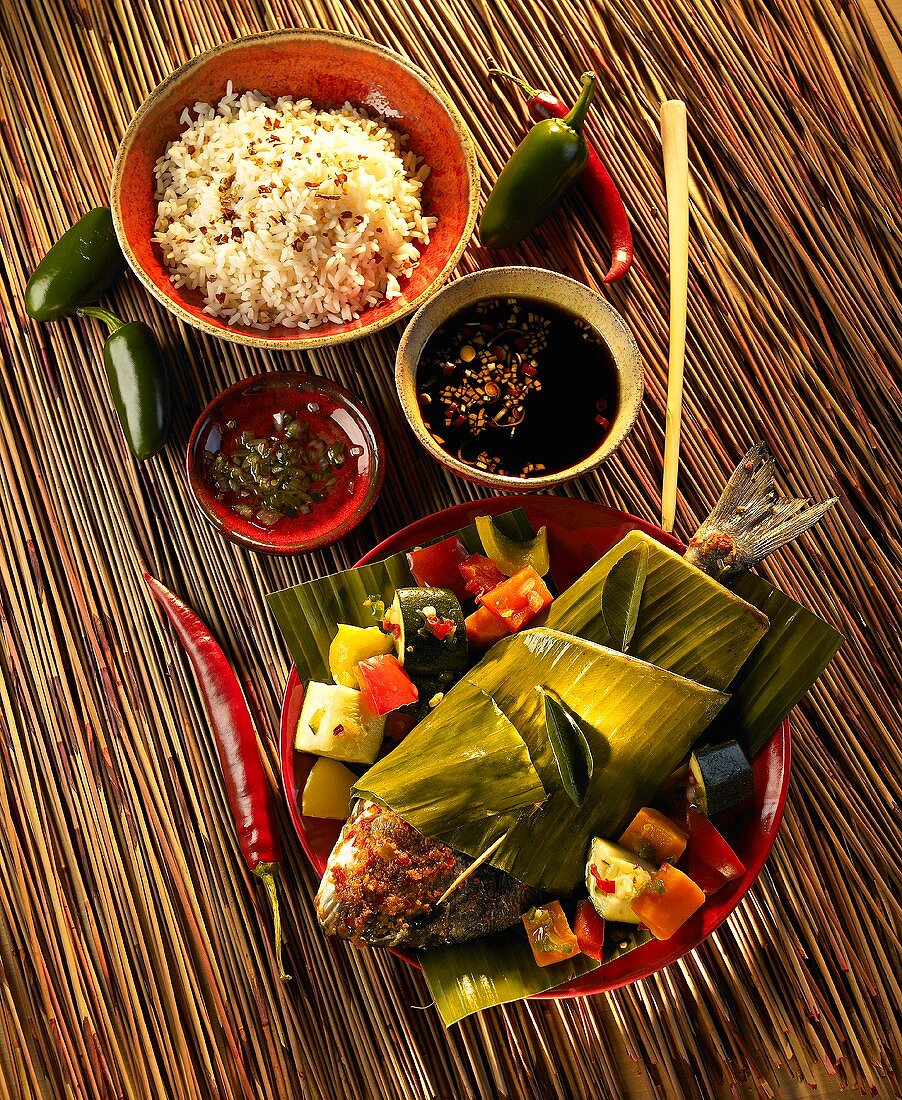 Gilt-head bream wrapped in a banana leaf with vegetables, rice and sauce (Indonesia)