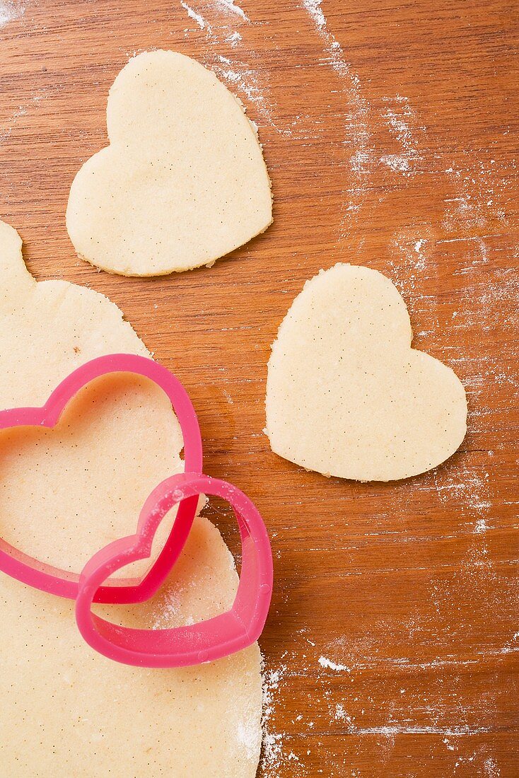 Unbaked, heart-shaped biscuits, biscuit dough and cutters