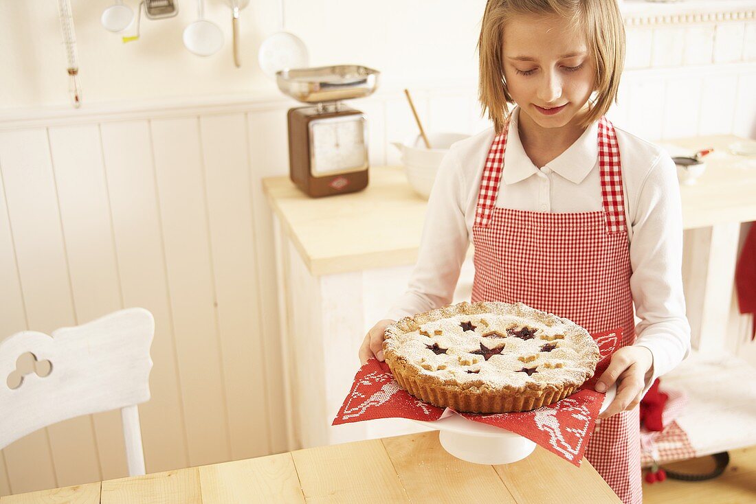 A girl serving a Christmas pie on a cake stand