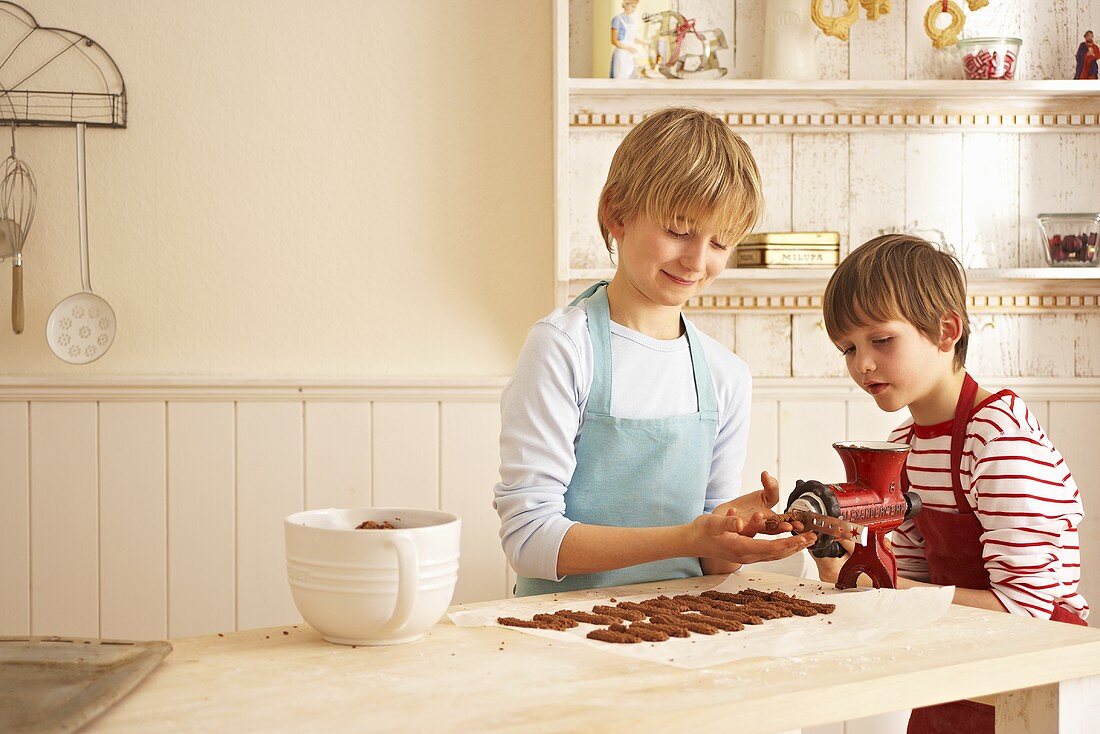 Children making chocolate Spritzgebäck (squirted biscuits)