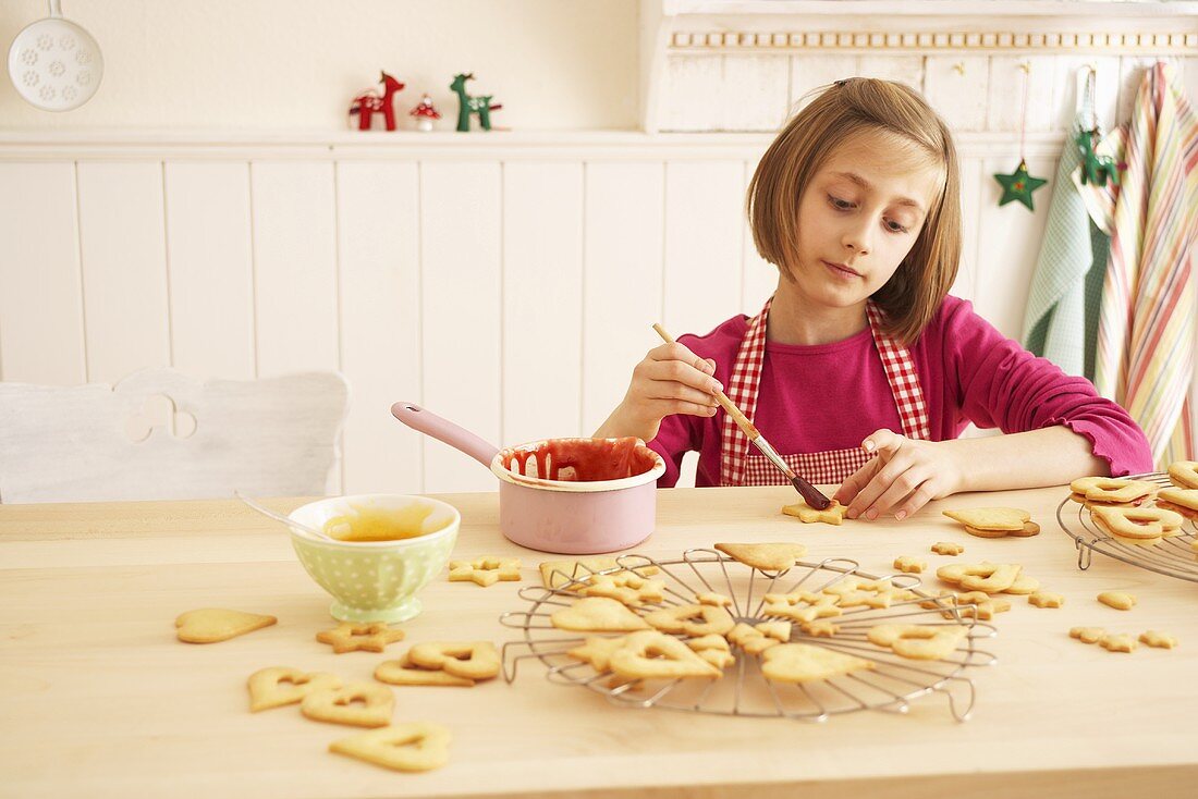 A girl brushing shortbread biscuits with jam