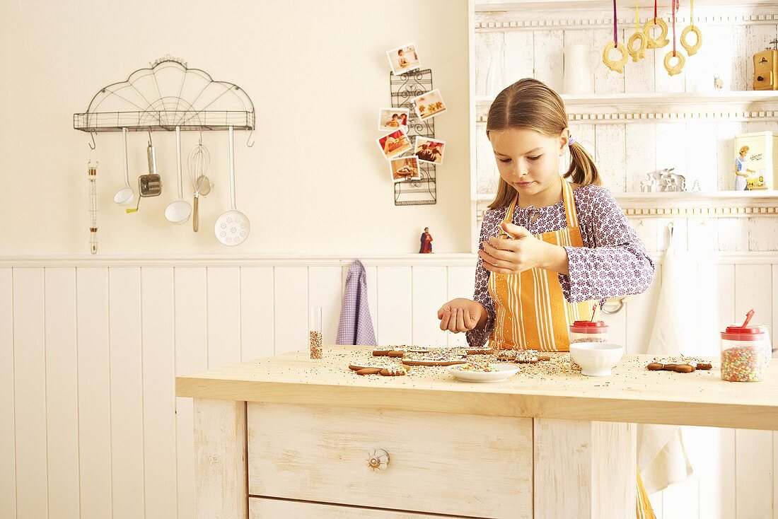 A girl decorating gingerbread with sugar strands