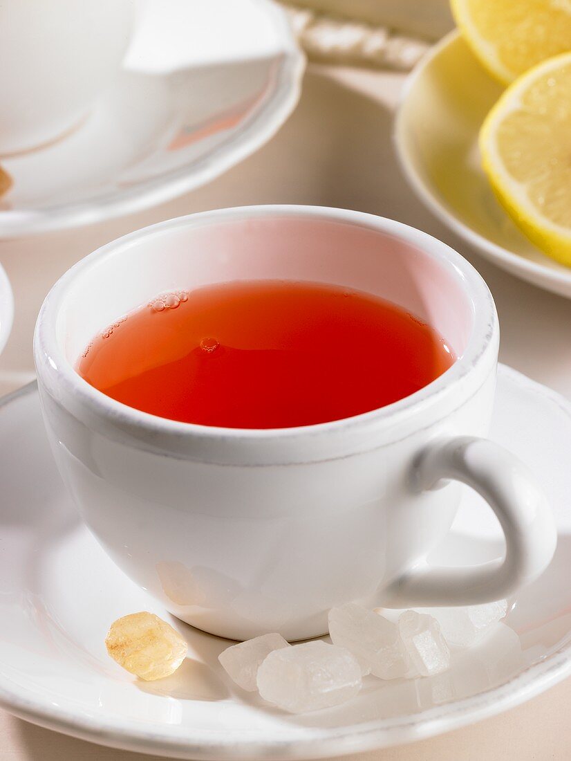 A cup of rosehip tea with candied sugar and lemon