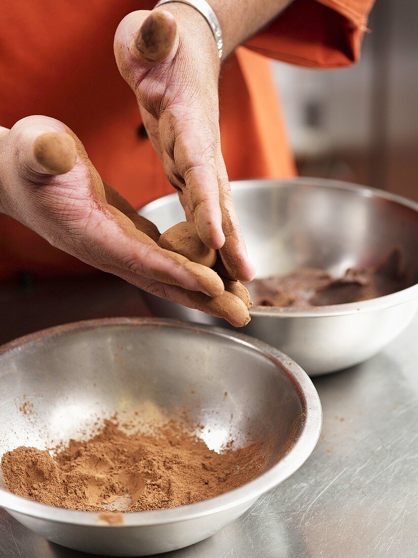 Truffle pralines being shaped and dusted with cocoa powder