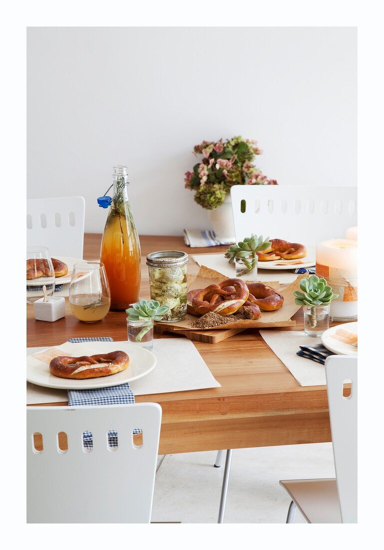 A table laid with prezels, cheese in oil and ginger drinks