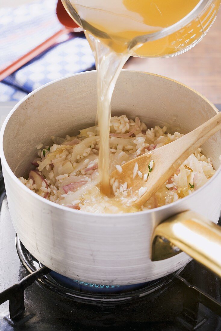 Chicory risotto being made: quenching with stock