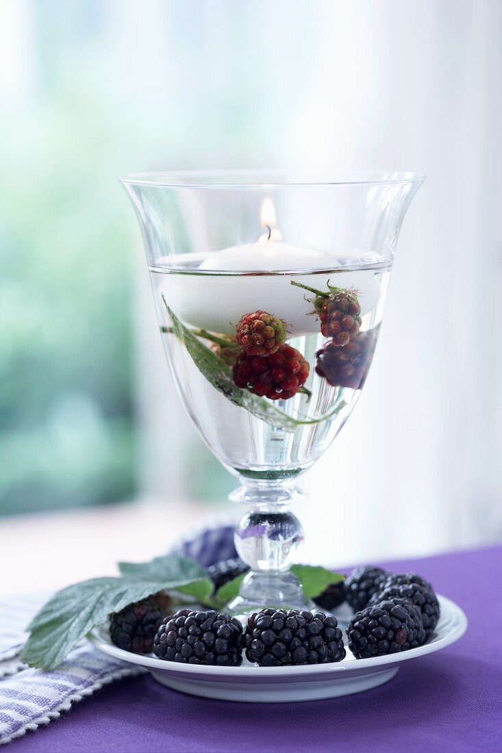 A wine glass being used as a lantern with blackberries