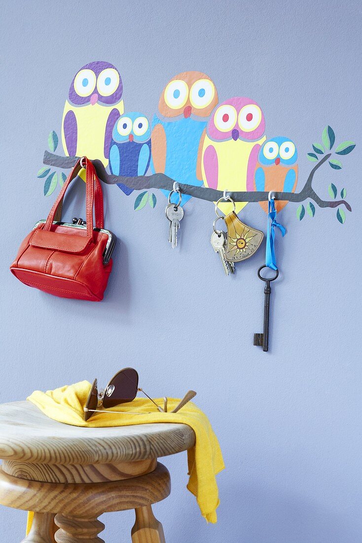 Owl wall stickers, key hooks, a bag and a scarf and sunglasses on a stool