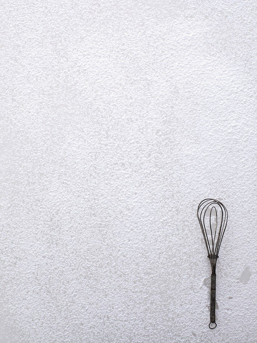 A whisk on icing sugar