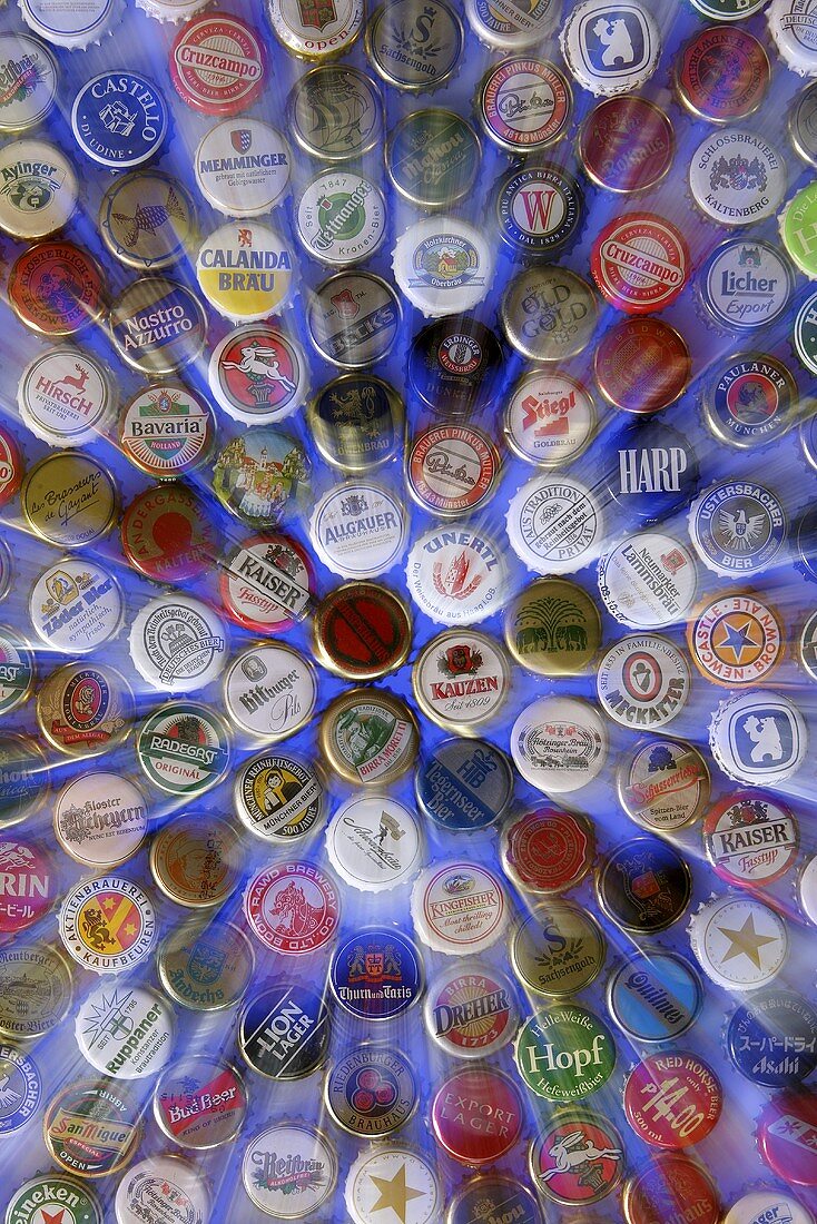 Bottle caps from different beers on blue background