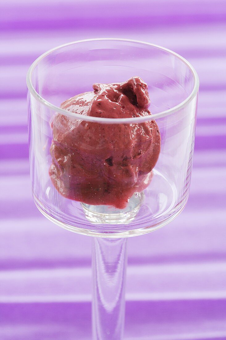 A scoop of blueberry ice cream in a glass