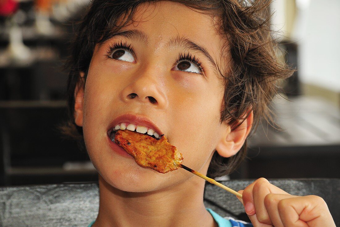 Boy eating chicken satay