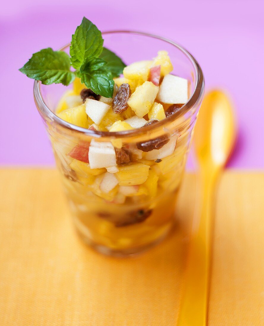 Fruit salad with raisins and mint in glass