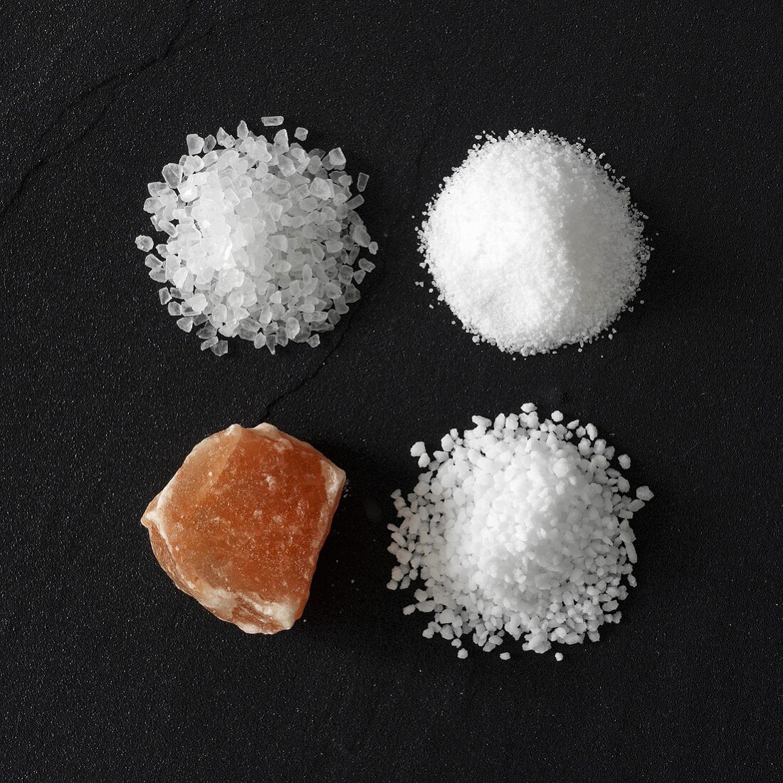 Vier verschiedene Salzsorten auf Steinuntergrund