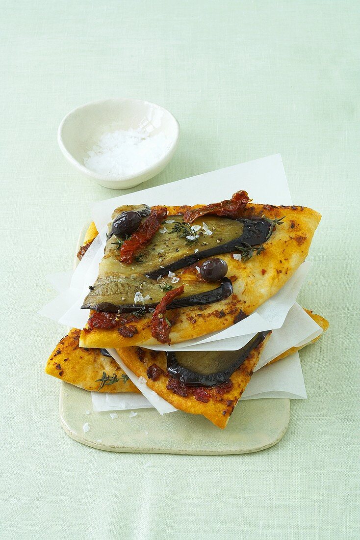 Pizzastücke mit getrockneten Tomaten und Oliven