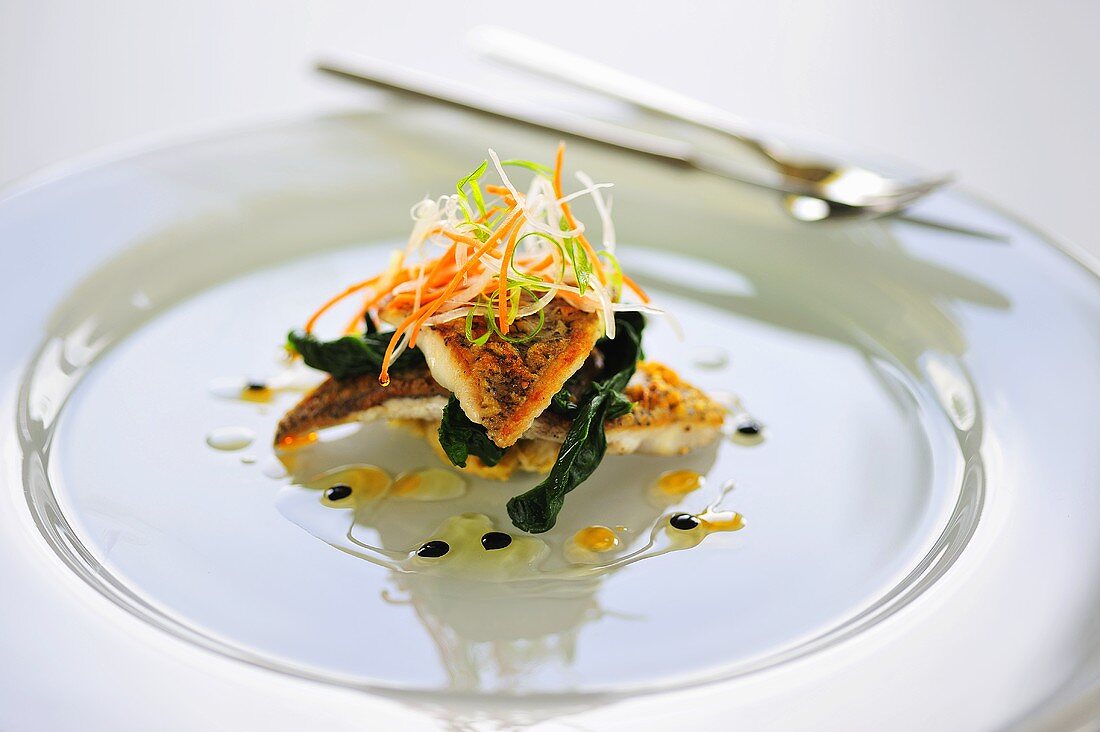 Sea bass fillets on spinach garnished with julienne vegetables