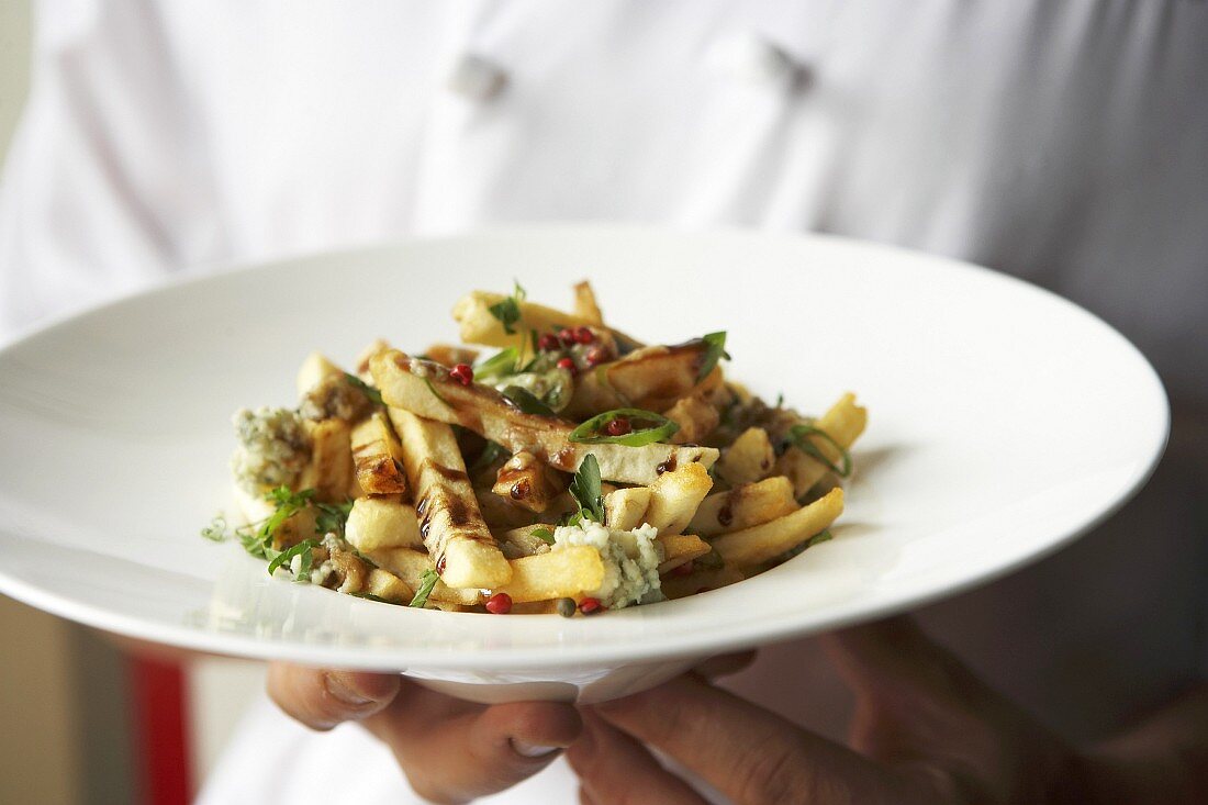 Koch serviert Poutine (Pommes mit Käse und Bratensauce, Kanada)