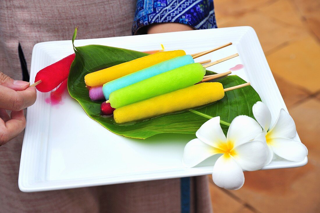 Woman carrying platter of coloured ice lollies