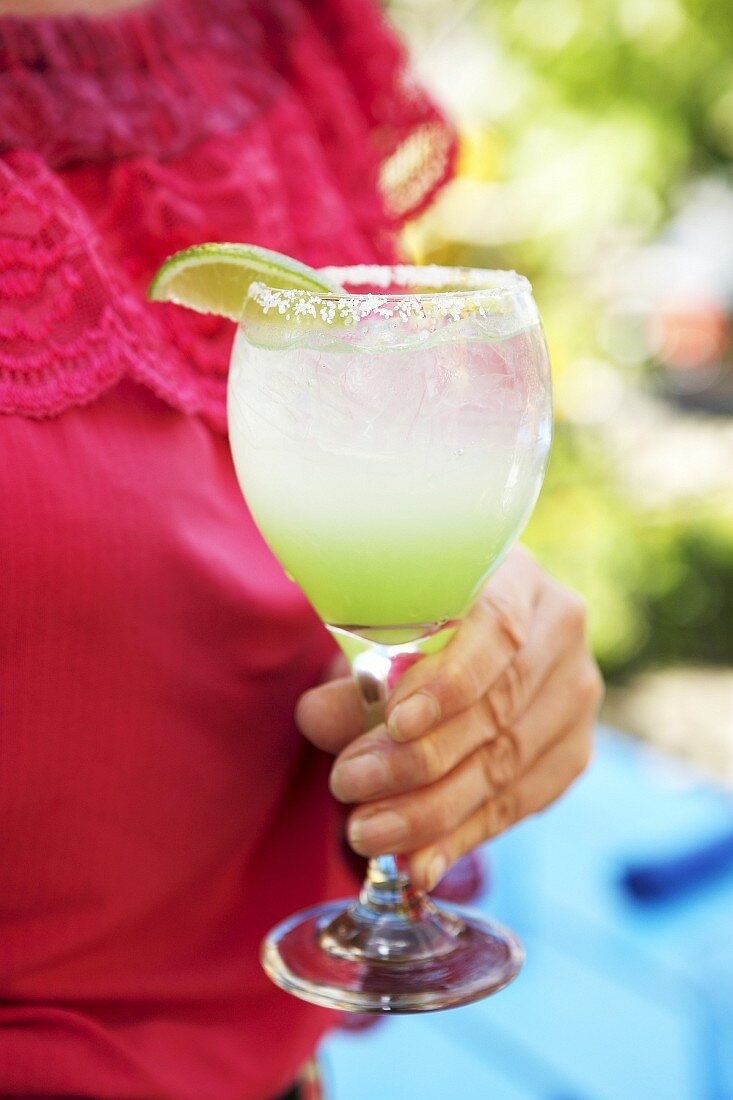 Frau hält ein Glas Lime Margarita in der Hand