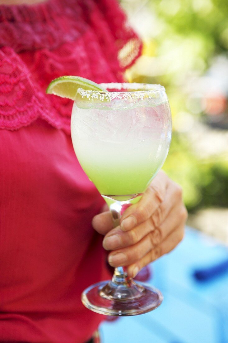 Woman holding a glass of Lime Margarita in her hand