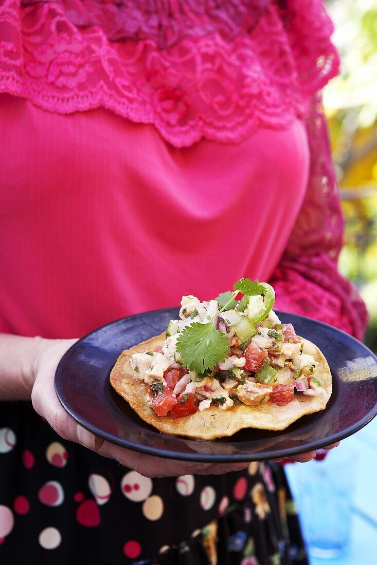 Woman holding plate of ceviche on flatbread