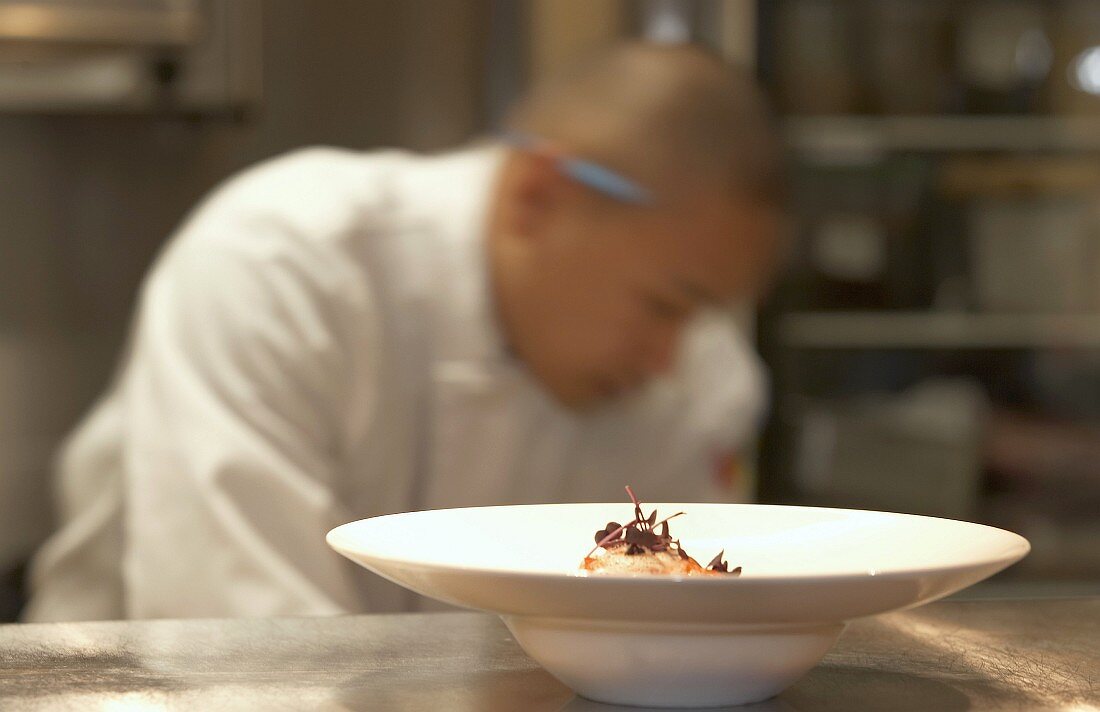 Chef plating a dish in a kitchen