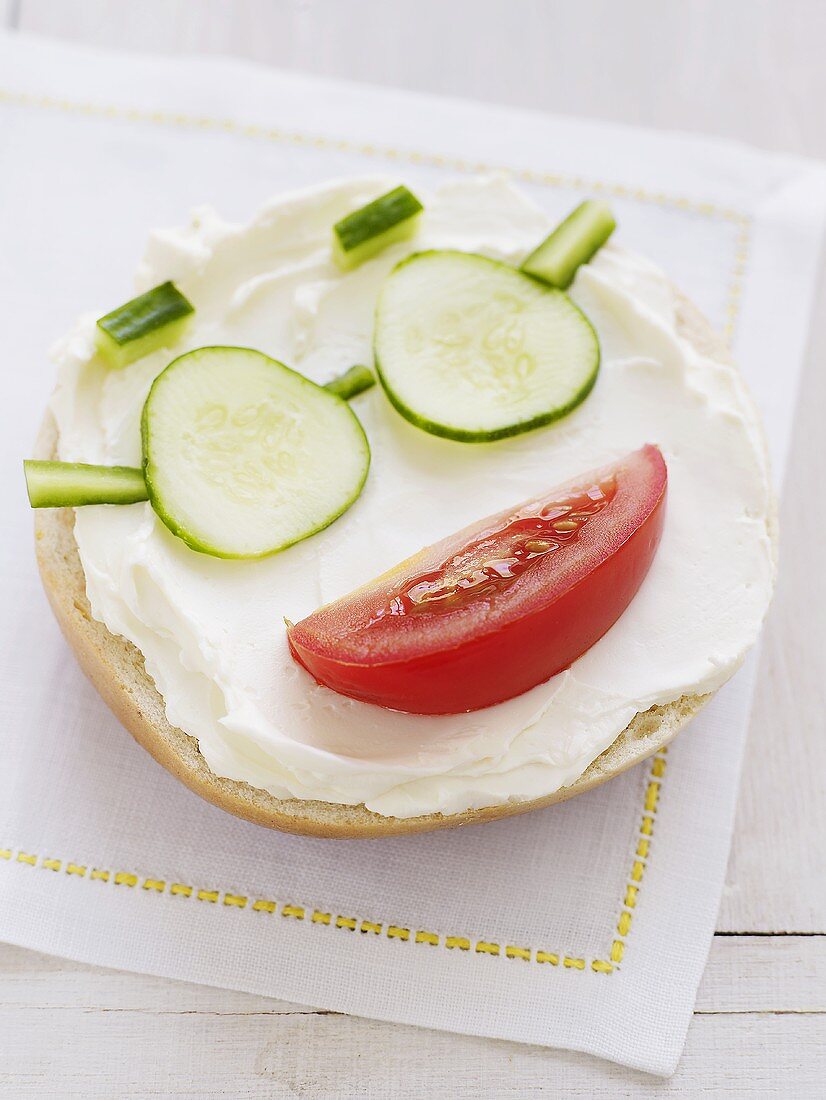 Bagel topped with cream cheese, tomato & cucumber (face)