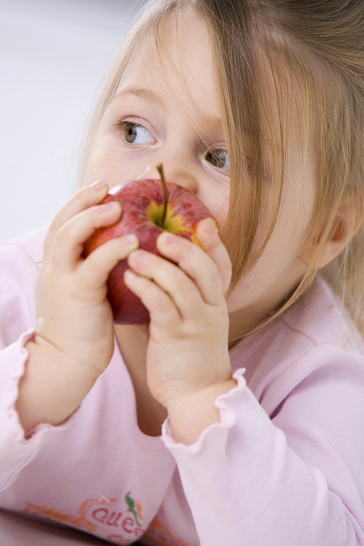 Kleines Mädchen isst einen Apfel