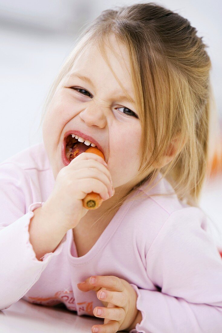 Kleines Mädchen isst eine Karotte
