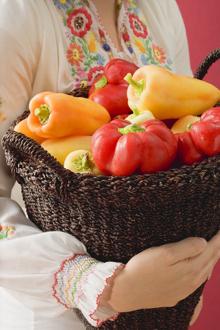 Woman holding basket of peppers (Hungary)