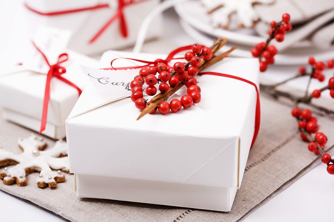 Päckchen mit rotem Geschenkband und Ilexbeeren