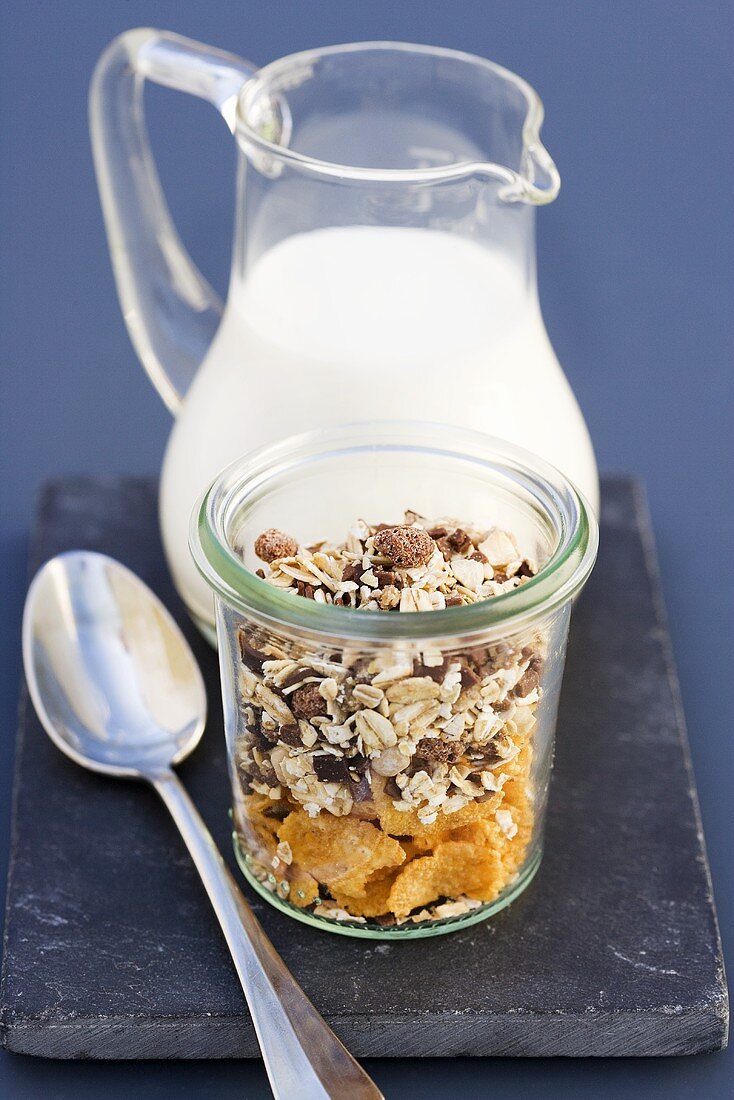 Cornflakes and muesli in a jar, jug of milk