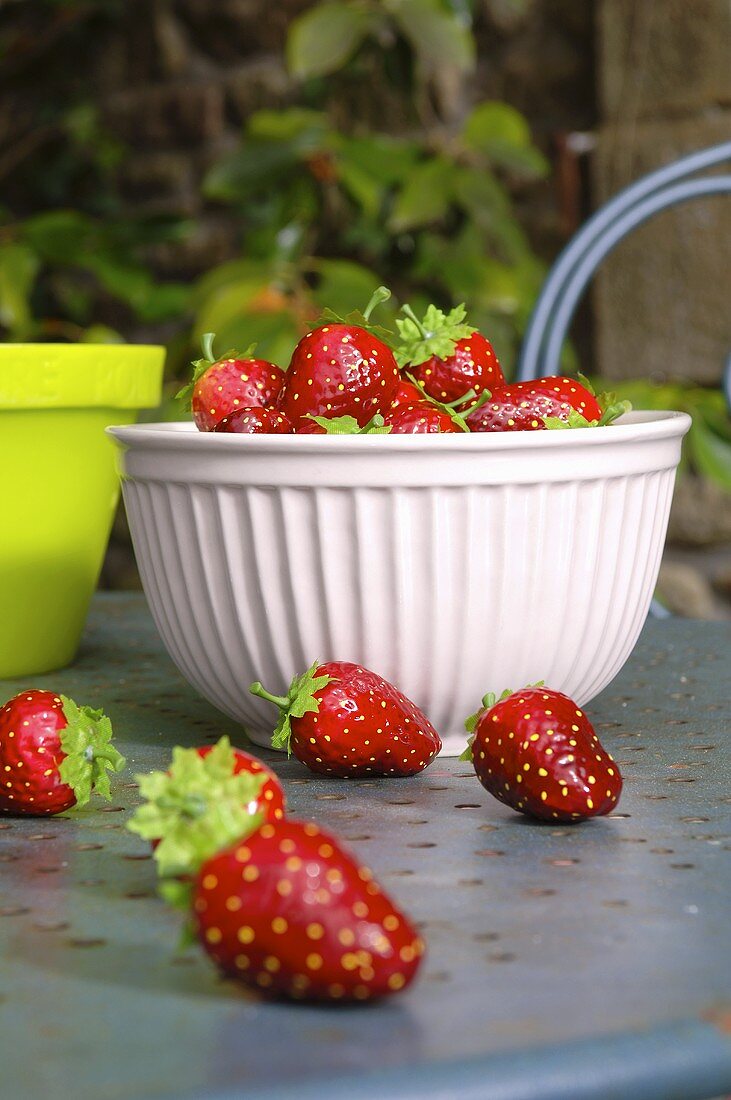 Schale mit Deko-Erdbeeren auf Gartentisch