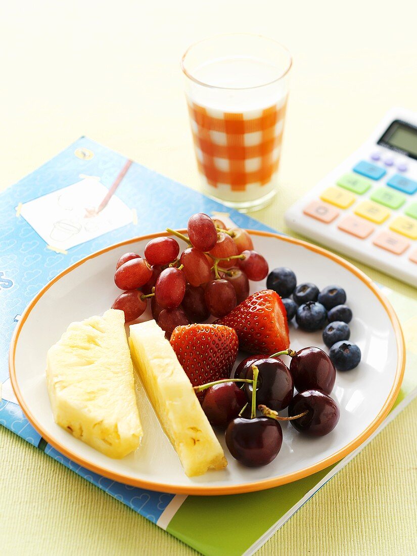 Obstteller und Glas Milch auf Schulheft