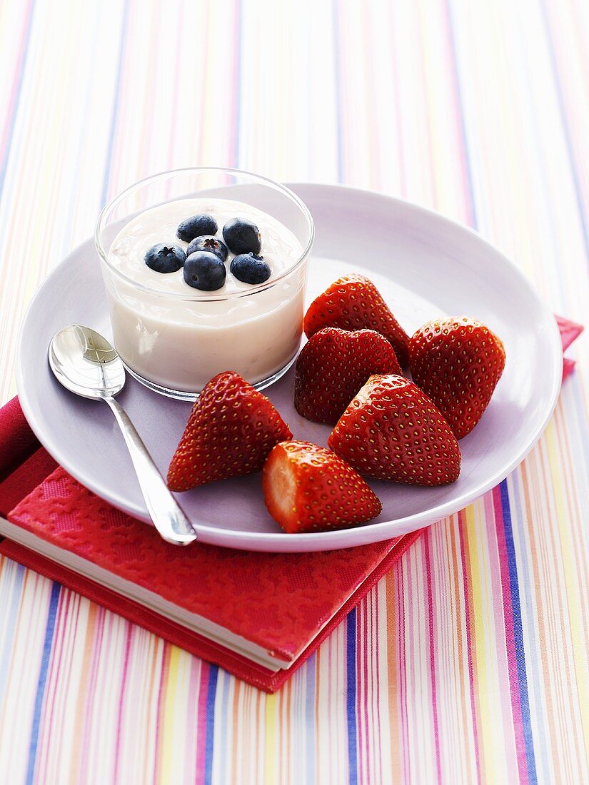 Heidelbeerjoghurt und Erdbeeren auf Notizbuch