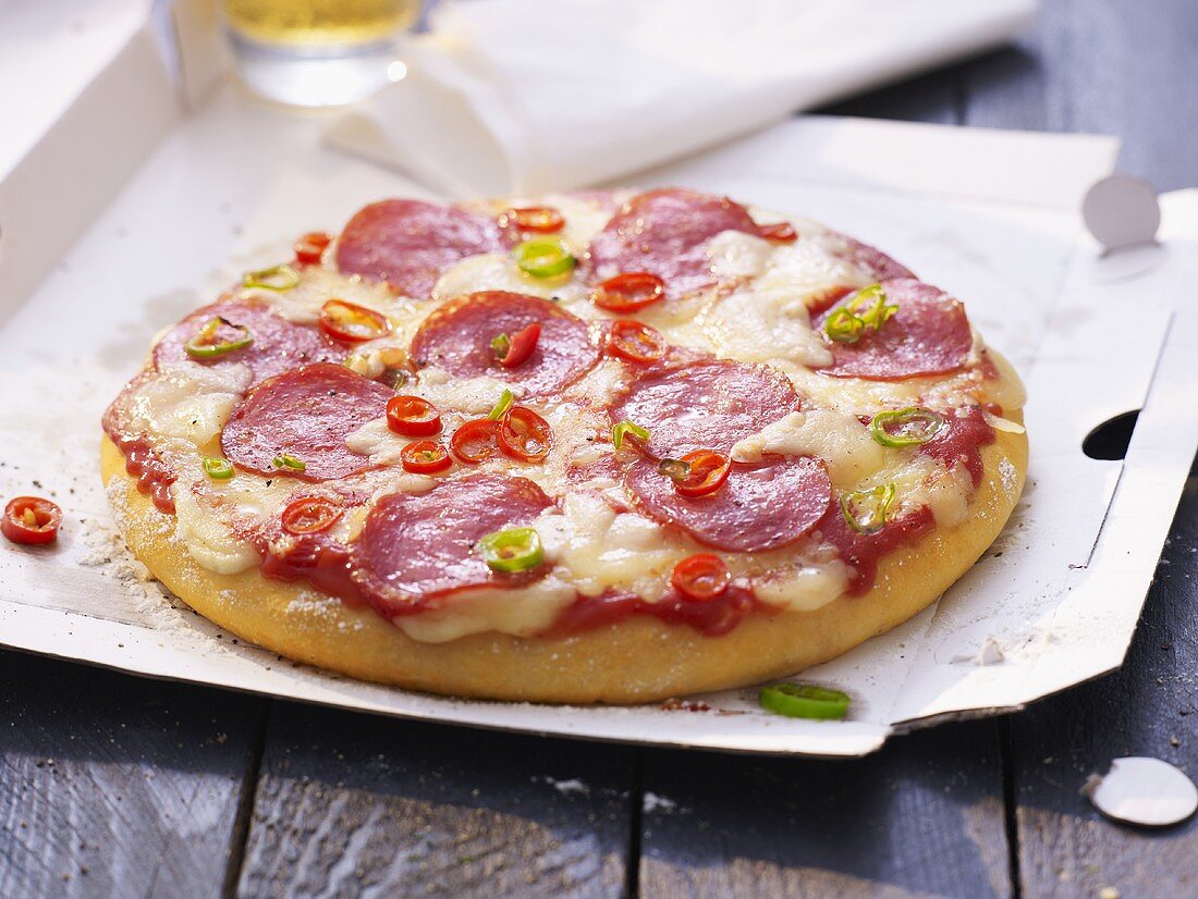 Salami pizza with chilli rings on pizza box