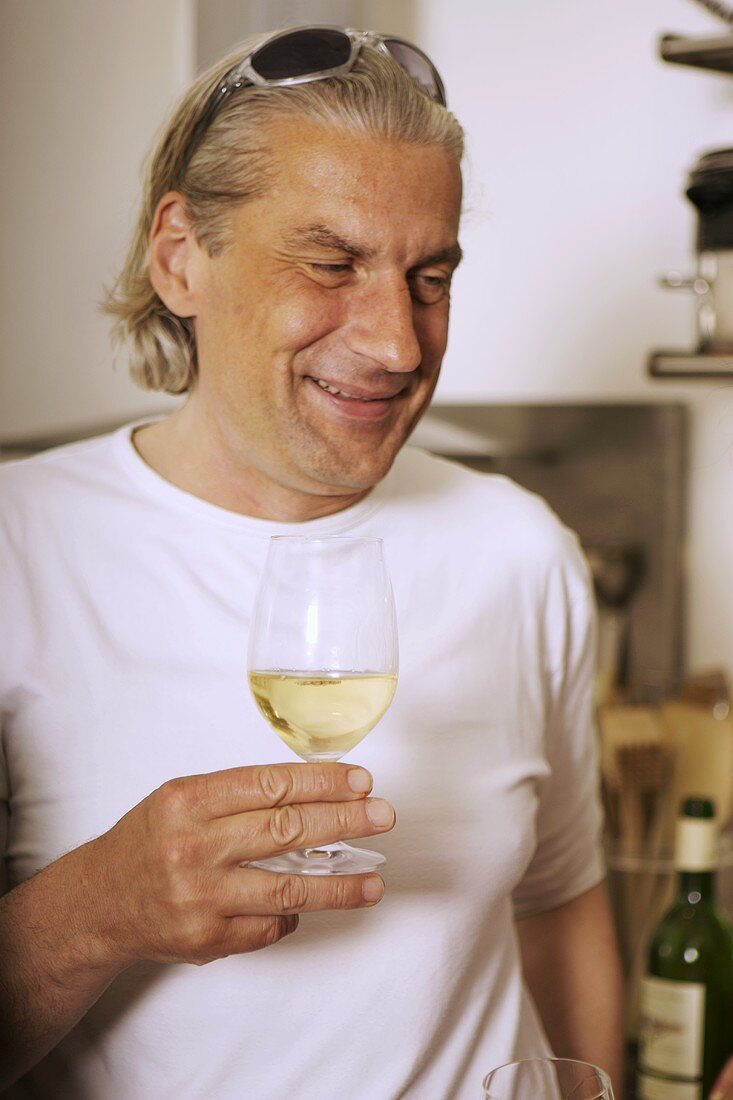 Grauhaariger Mann trinkt Weißwein