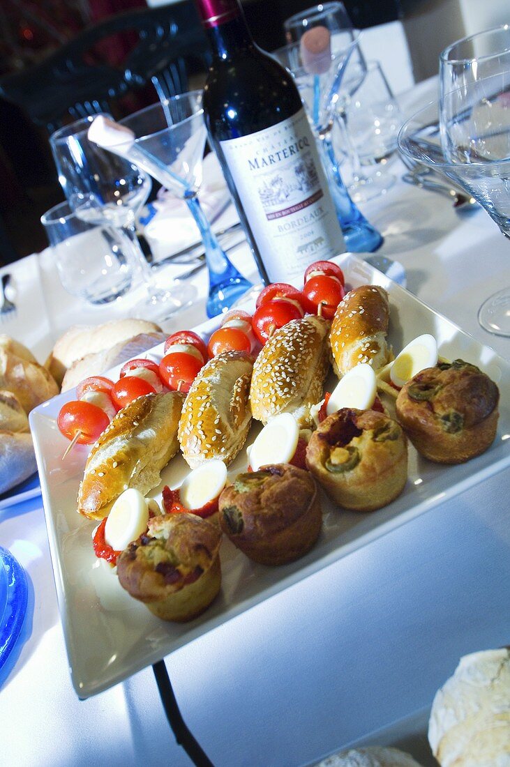 A tray of spicy pastries, boiled eggs, kebabs and a bottle of red wine