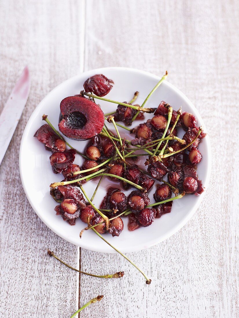Cherry stones and stalks and half a cherry on plate
