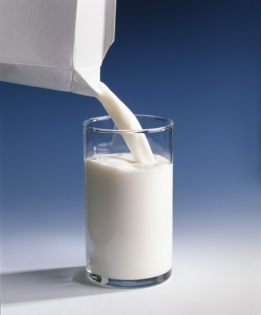 Milch aus Tetrapack in Glas gießen