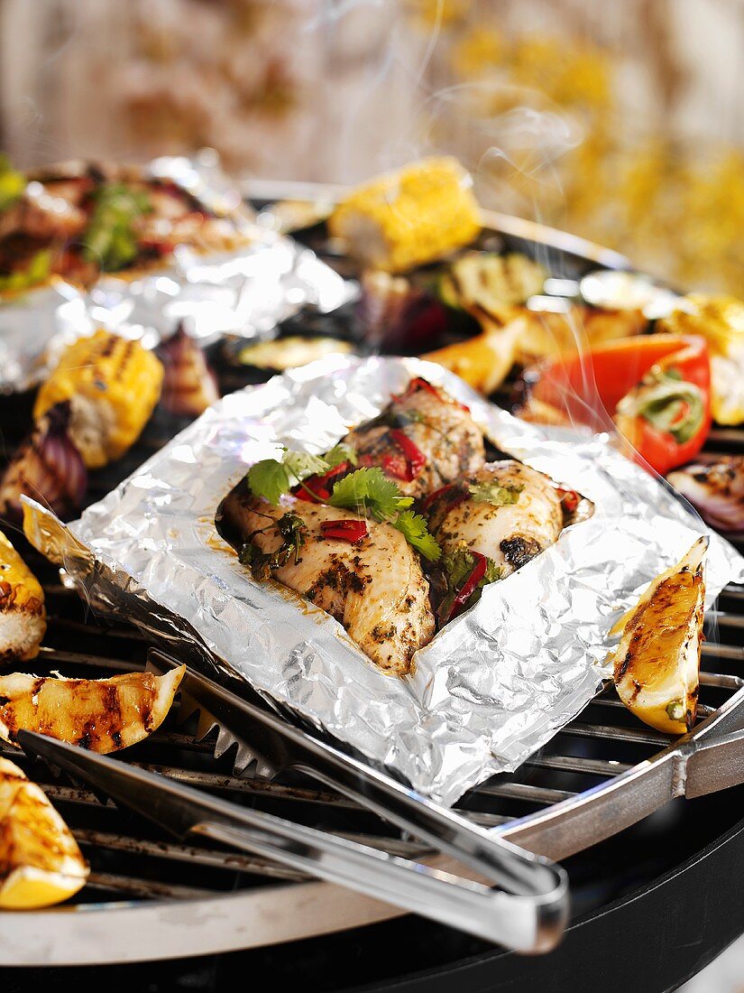 Chicken in aluminium foil on barbecue rack