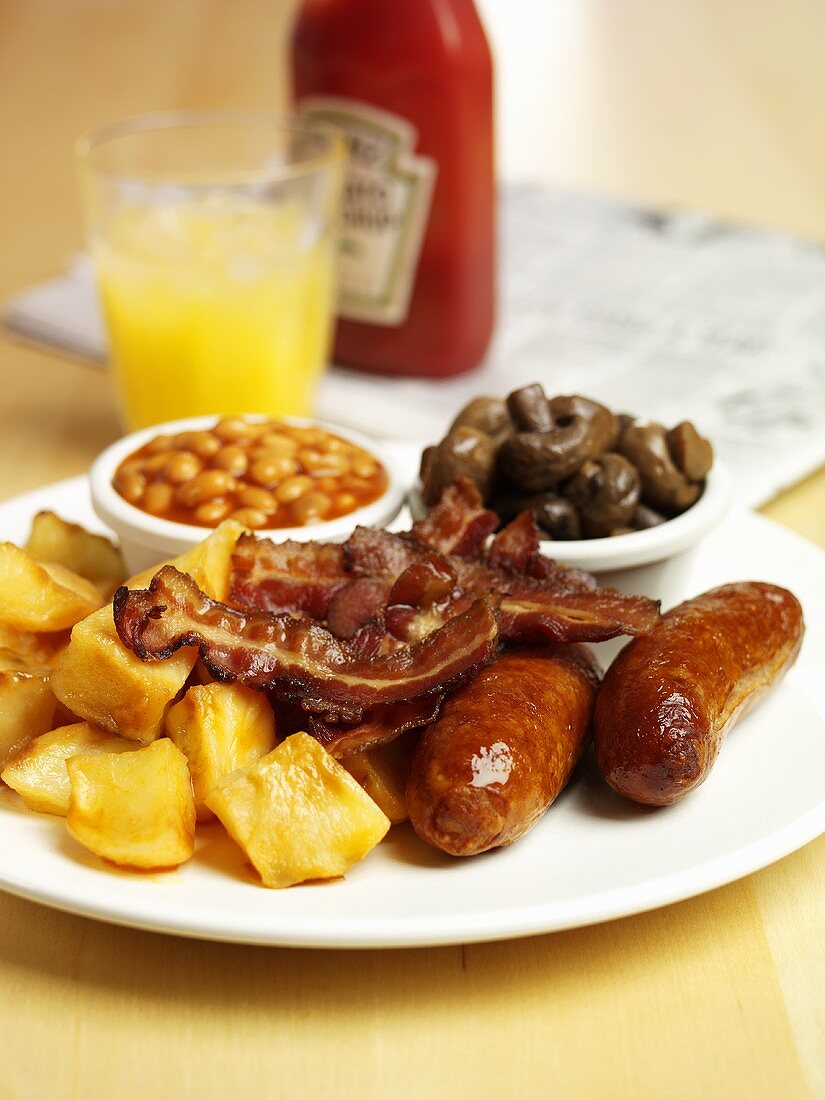 Cooked breakfast: sausages, bacon, fried potatoes, baked beans
