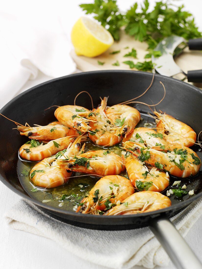 Fried king prawns with garlic and parsley in frying pan