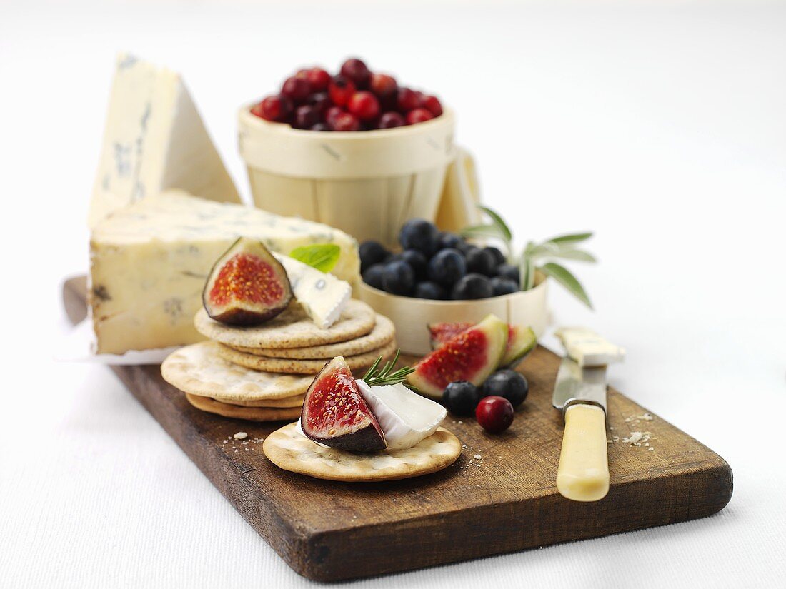 Cracker mit Blauschimmelkäse, Feigen und Beeren auf Schneidebrett