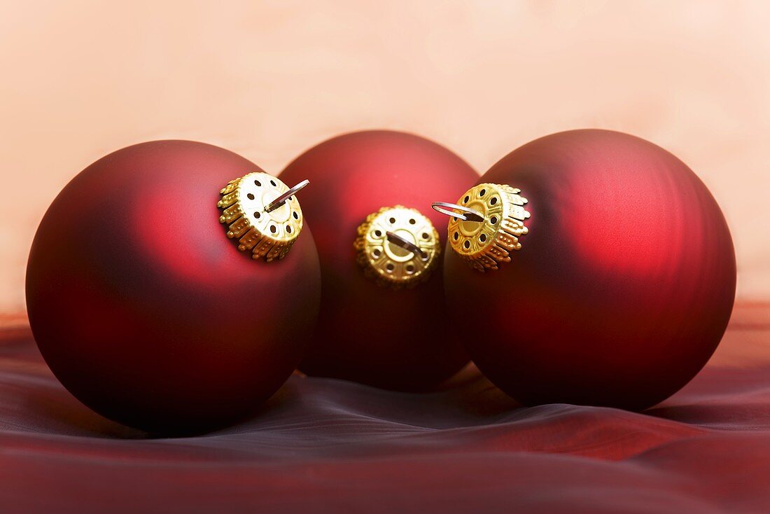 Three dark red Christmas baubles