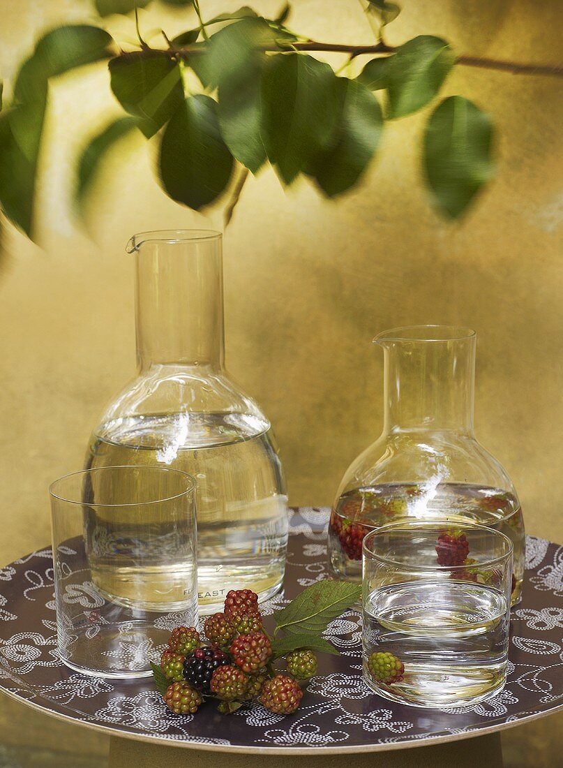 Water and blackberries in glasses and carafes