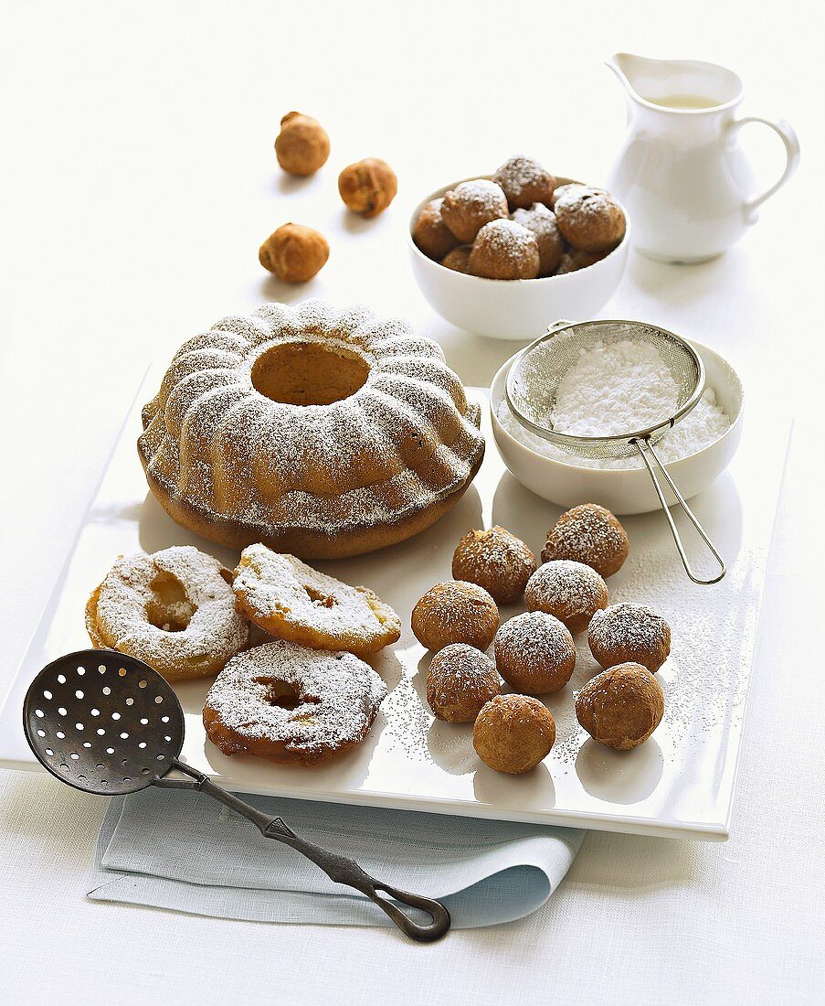 Ring cake, apple fritters and dough balls with icing sugar