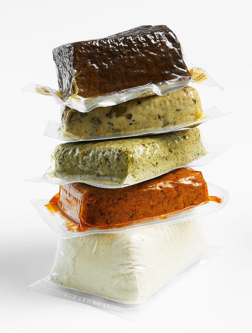 Various types of tofu in plastic packaging (plain, rosso, olive, basil, smoked)