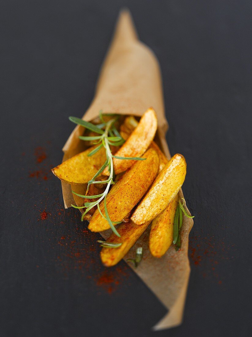 Potato wedges with paprika & rosemary in baking parchment cone